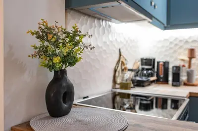 a black vase with flowers on a table in a kitchen at Stylish Koukaki Retreat by the Acropolis in Athens