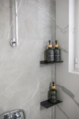 a bathroom with three bottles of soap sitting on shelves at Stylish Koukaki Retreat by the Acropolis in Athens