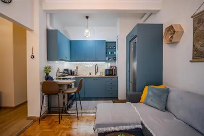 a living room with a couch and a kitchen with blue cabinets at Stylish Koukaki Retreat by the Acropolis in Athens