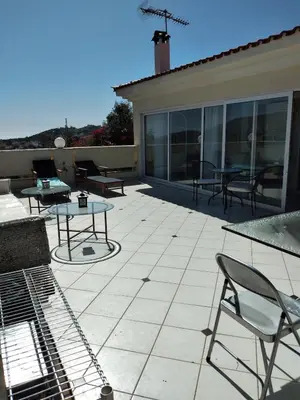 a patio with tables and chairs on a house at Penthouse Peaceful Oasis in Lagonissi