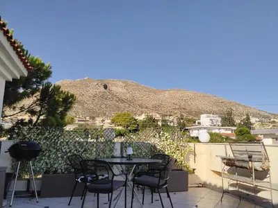 a patio with a table and chairs and a mountain at Penthouse Peaceful Oasis in Lagonissi