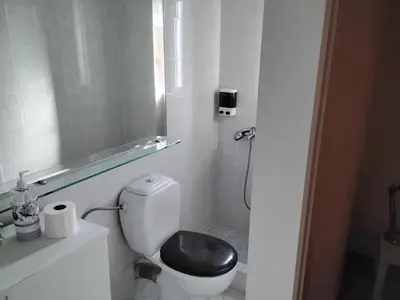 a bathroom with a toilet with a black seat at Penthouse Peaceful Oasis in Lagonissi