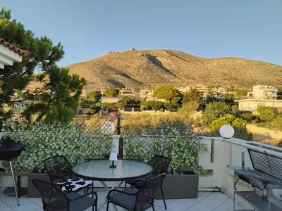 a patio with a table and chairs and a mountain at Penthouse Peaceful Oasis in Lagonissi