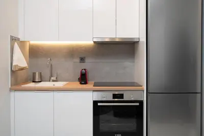 a kitchen with white cabinets and a sink and a refrigerator at Unique Urban Gem in Neapoli Exarcheia in Athens