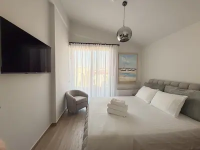 a white bedroom with a bed and a couch at The Mint House - Alimos in Athens