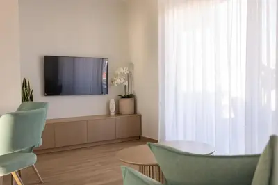 a living room with a flat screen tv and chairs at The Mint House - Alimos in Athens