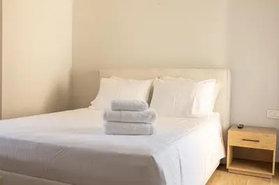 a white bed with three towels stacked on it at The Mint House - Alimos in Athens
