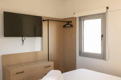 a bedroom with a tv and a bed and a window at The Mint House - Alimos in Athens