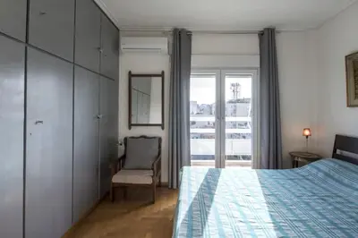 a bedroom with a bed and a chair and a window at Home away from Home in Athens