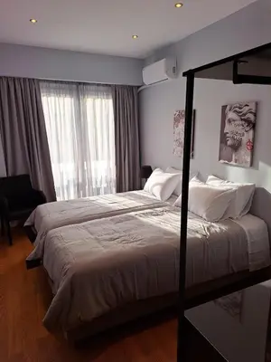 a bedroom with two beds and a large window at TrilogyCentral in Athens