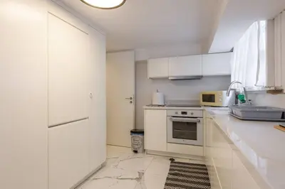 a white kitchen with white cabinets and a sink at Zeus1 beach front appatment, 1BR sea view in Athens