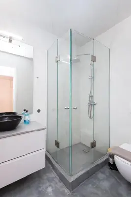 a glass shower in a bathroom with a sink at Zeus2 Beach Front Apartment, 3BR in Athens