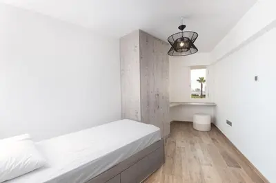 a white bedroom with a bed and a chandelier at Zeus2 Beach Front Apartment, 3BR in Athens