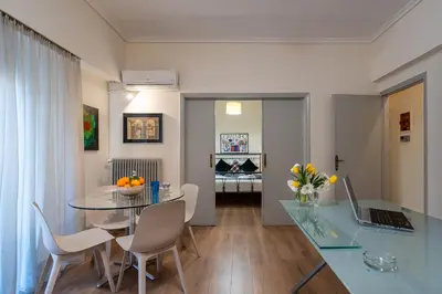 a dining room with a glass table and a laptop at Didotου Apartments in Athens