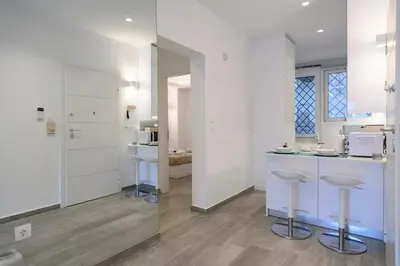 a kitchen with white cabinets and bar stools at Icarus Minimal 2bedroom Bliss in Athens