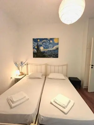 two beds in a room with a painting on the wall at Apartment next to the sea in Anavissos
