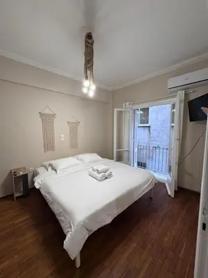 a bedroom with a large white bed and a window at KOYKAKI MODERN RETREAT 250m FROM ACROPOLIS in Athens