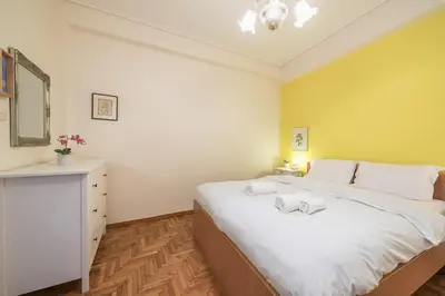a bedroom with a large white bed and a dresser at Charming Apartment near Acropolis 100mbps WiFi in Athens