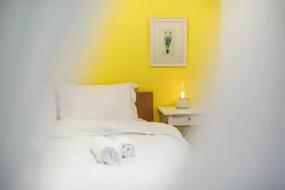 a bedroom with a white bed and a yellow wall at Charming Apartment near Acropolis 100mbps WiFi in Athens