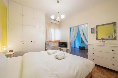 a white bedroom with a white bed and a television at Charming Apartment near Acropolis 100mbps WiFi in Athens
