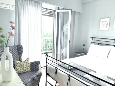 a bedroom with a bed and a chair and a window at Acropolis, 2BD Erechthiou 21 23 in Athens