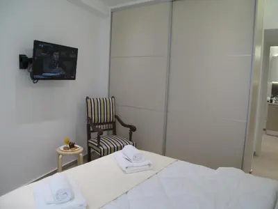 a bedroom with a bed and a chair and a tv at Parthenonas in Athens