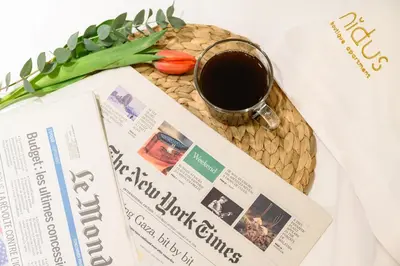 a newspaper and a cup of coffee and a magazine at Nidus Boutique Apartment in Athens