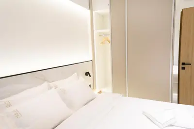 a white bed with white pillows and a mirror at Nidus Boutique Apartment in Athens