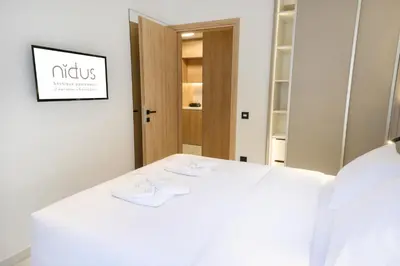 a white bed in a room with a mirror at Nidus Boutique Apartment in Athens