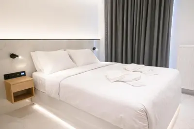 a hotel room with a white bed and a night stand at Nidus Boutique Apartment in Athens