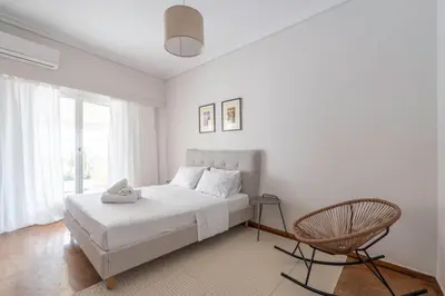 a white bedroom with a bed and a chair at Maison Terrasse - Georgeous 3Br Apt next to Acropolis in Athens