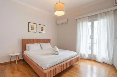 a bedroom with a bed with white sheets and a window at Maison Terrasse - Georgeous 3Br Apt next to Acropolis in Athens