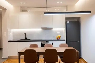 a kitchen with a table and chairs and a black refrigerator at Vibrant Pagrati 2-BD Retreat with Elegant-Modern style in Athens