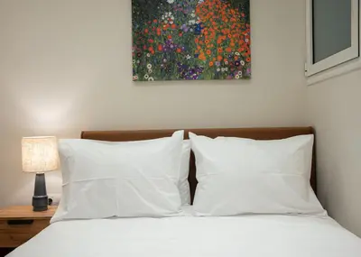 a bed with white pillows and a painting on the wall at Vibrant Pagrati 2-BD Retreat with Elegant-Modern style in Athens
