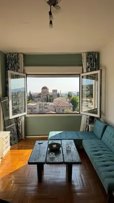 a living room with a couch and a table and a window at The Green Parthenon in Athens