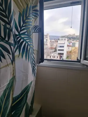 a bathroom with a window with a leaf patterned shower curtain at The Green Parthenon in Athens