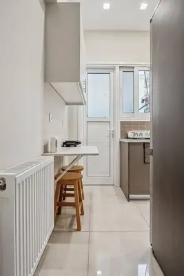 a white kitchen with a counter and a table at Athene Appartment in Athens