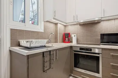 a kitchen with white cabinets and a sink and a microwave at Athene Appartment in Athens