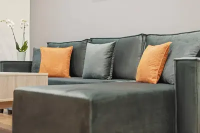 a gray couch with orange and gray pillows on it at Athene Appartment in Athens