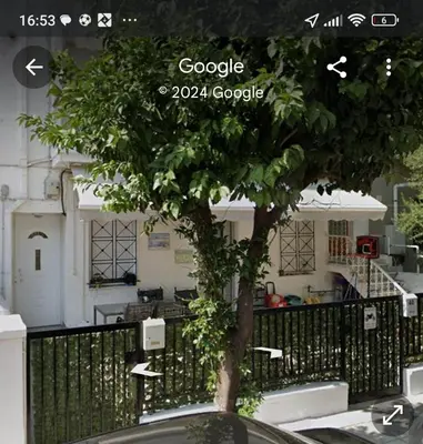 a tree sitting in front of a house at Seaside Resort in Piraeus