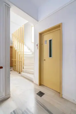 a hallway with a yellow door and stairs at Glyfada Center Front Seaview Studio A in Athens