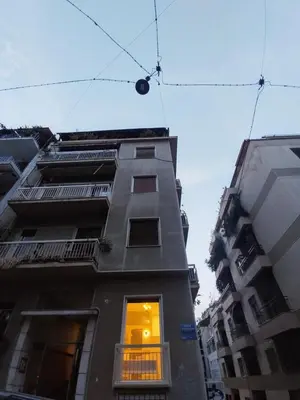 a tall building with a light in the window at AMG Kalimarmaro Small Apartment in Pagkrati Close to Metro in Athens