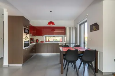 a kitchen with a table and chairs and red cabinets at Luxury modern villa with swimming pool, Athens Riviera in Lagonissi
