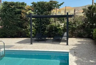 a gazebo with two chairs and a swimming pool at Luxury modern villa with swimming pool, Athens Riviera in Lagonissi