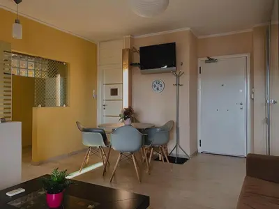 a living room with a table and chairs and a television at Einstein Apartment in Athens
