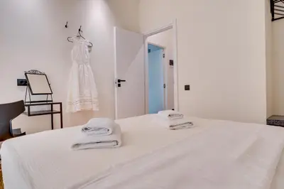 a white bedroom with a dress hanging on a wall at Athens Marbles-Classic suite in Athens