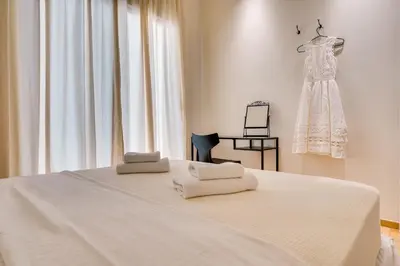 a white bed with towels on it with a dress on a rack at Athens Marbles-Classic suite in Athens