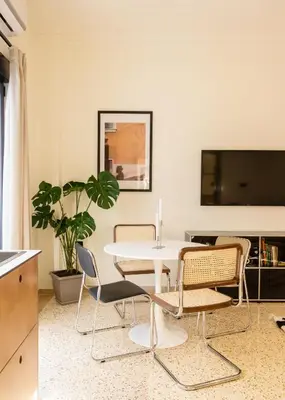 a dining room with a table and chairs and a tv at The Athenette in Athens