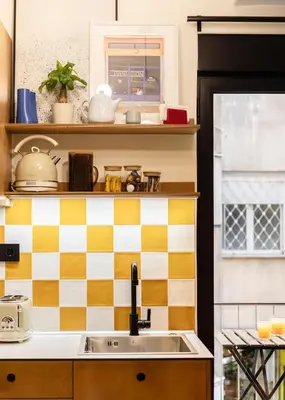 a kitchen with a sink and a checkered wall at The Athenette in Athens