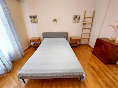 a bed in a room with a wooden floor at Cozy apartment in Pagkrati in Athens